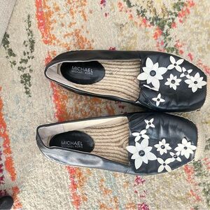 MICHAEL Michael Kors Black Leather Floral Appliqué Slip-Ons with White Flowers